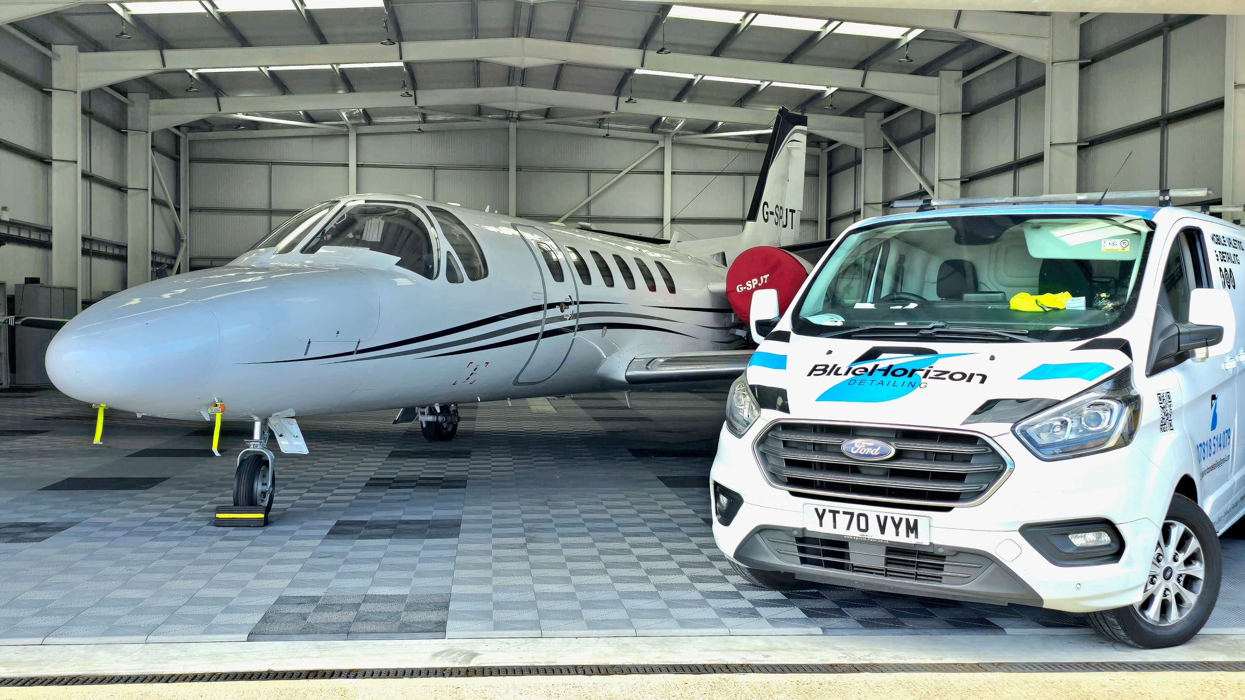 A freshly detailed Citation business jet in a hangar with the Blue Horizon service van parked alongside