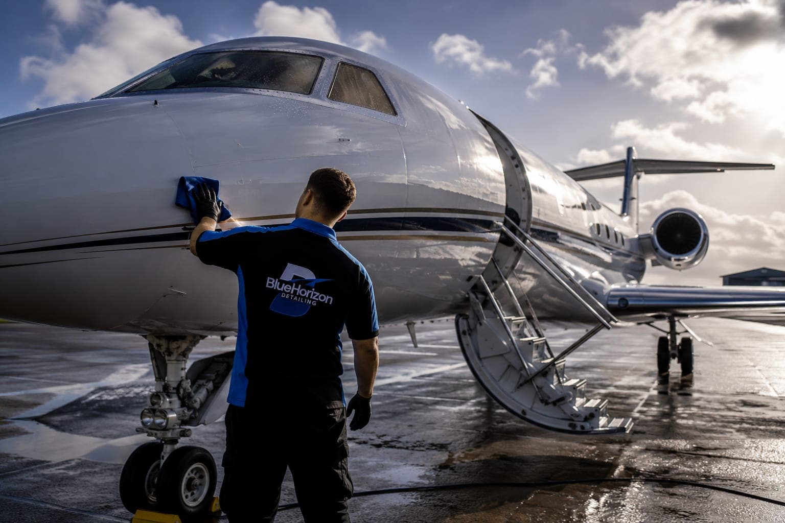 A Blue Horizon technician wiping down a business jet's nose on a wet apron